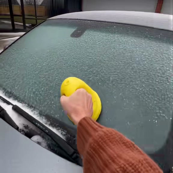 Hand guiding the yellow electric scraper over frost on a car windshield